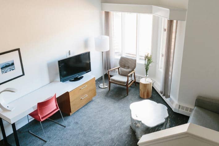 An view from above into a lounge with a TV, chairs and couch next to a bright window.