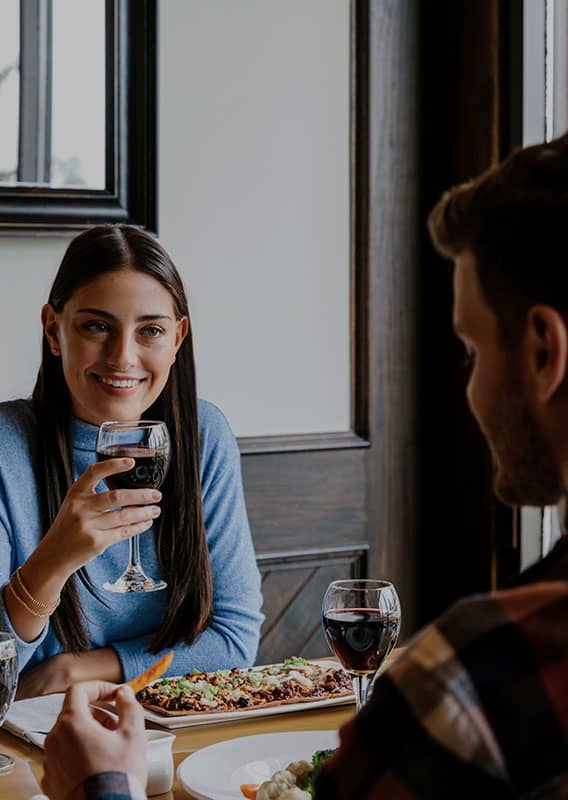 Two people sit for dinner with wine