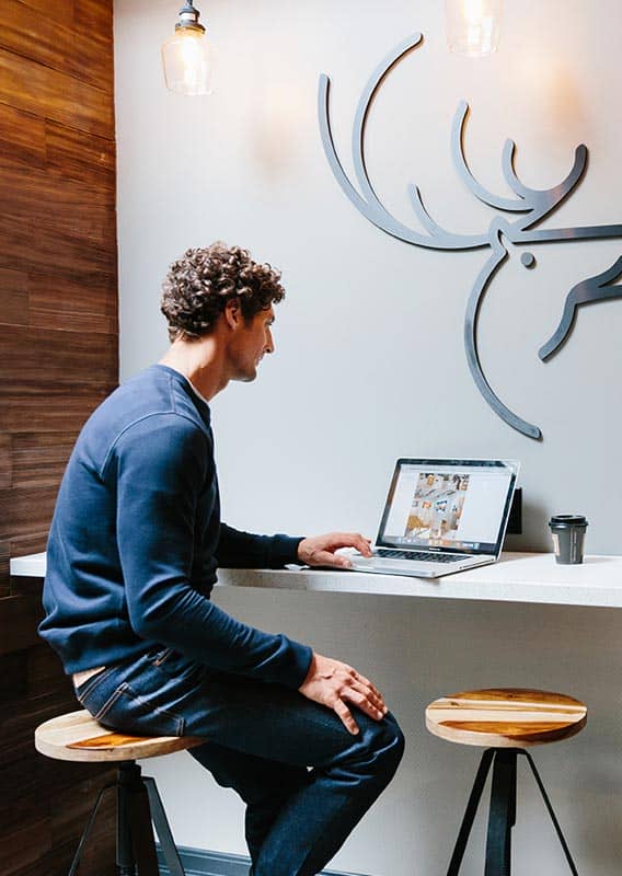 A person sits at a countertop desk with a laptop computer.