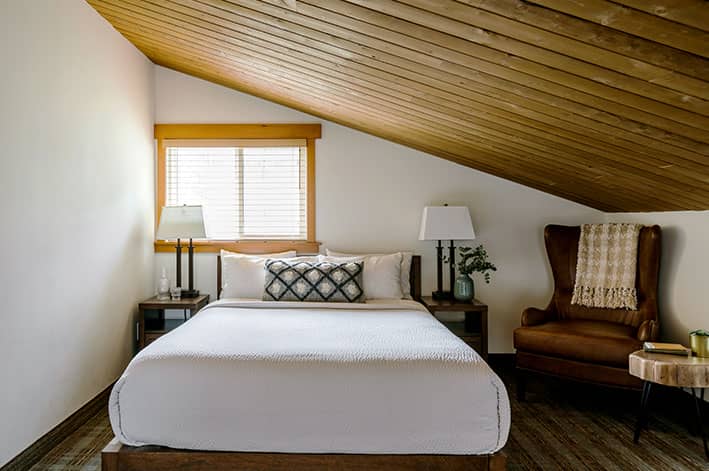 A bed and sitting chair in a hotel room.