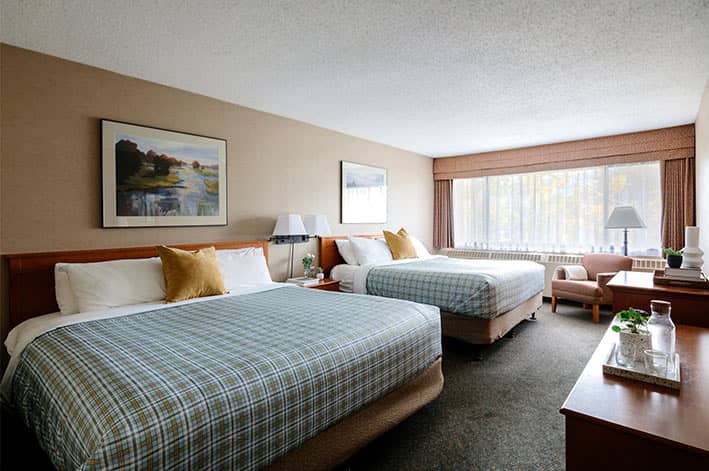 Two king beds in a hotel room with wide window