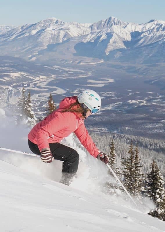 A skier goes down a steep snowy slope.