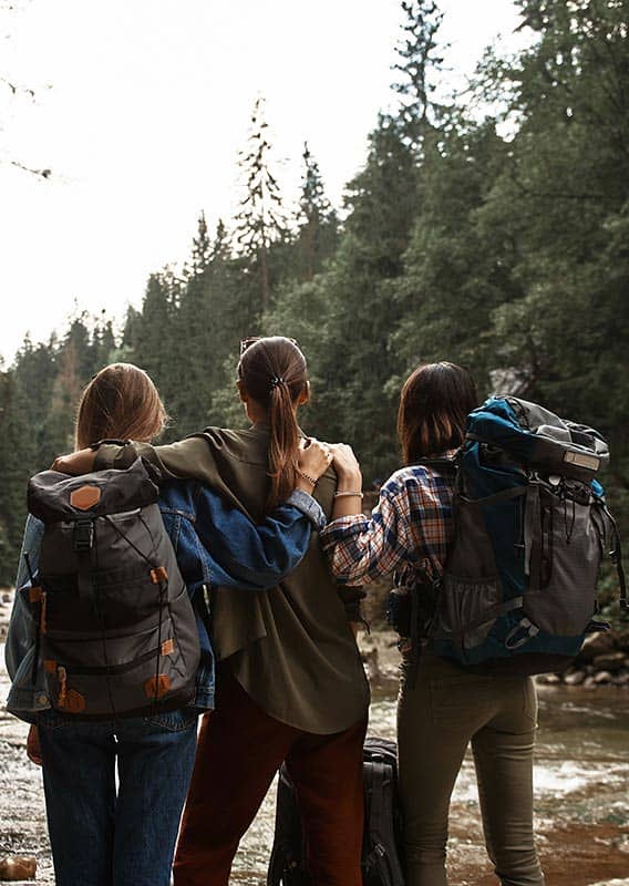 Three women face a river upstream