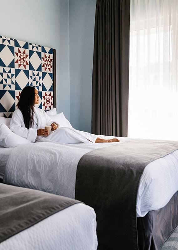 woman sitting in bed looking out window