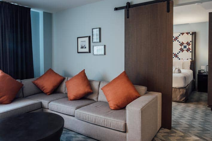 An L-shaped couch near a door leading into a bedroom.