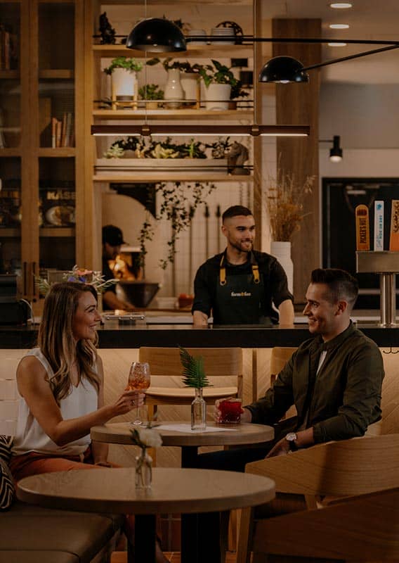 Groups of people dine at a restaurant table and bar.