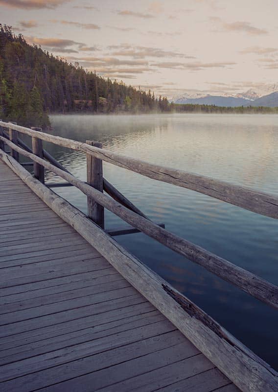 A view from a wooden bridge across a calm lake.