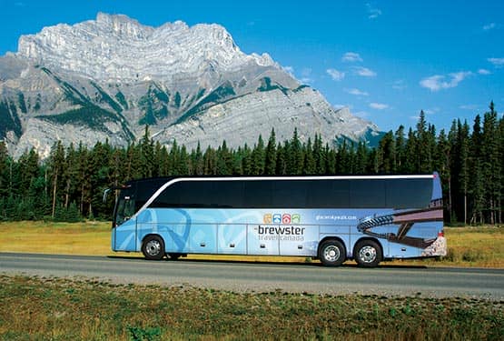 Brewster motor coach driving on a road at the base of mountain