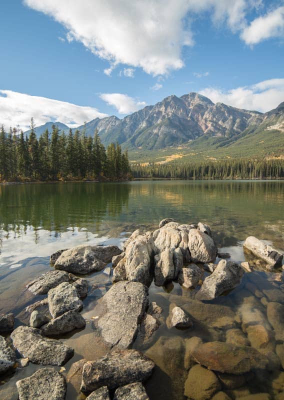 View of a tall forest-covered mountain above a lake.