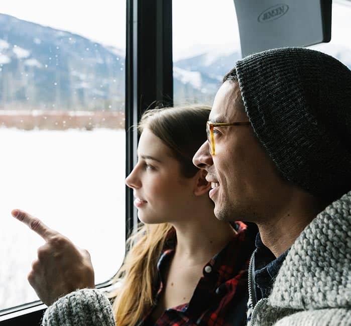 Two people sit at a bus window, looking at a winter landscape.