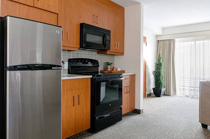 A kitchen with full refrigerator, oven and microwave