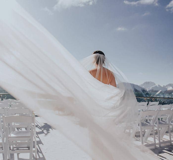 A bride walks on a high mountain balcony.