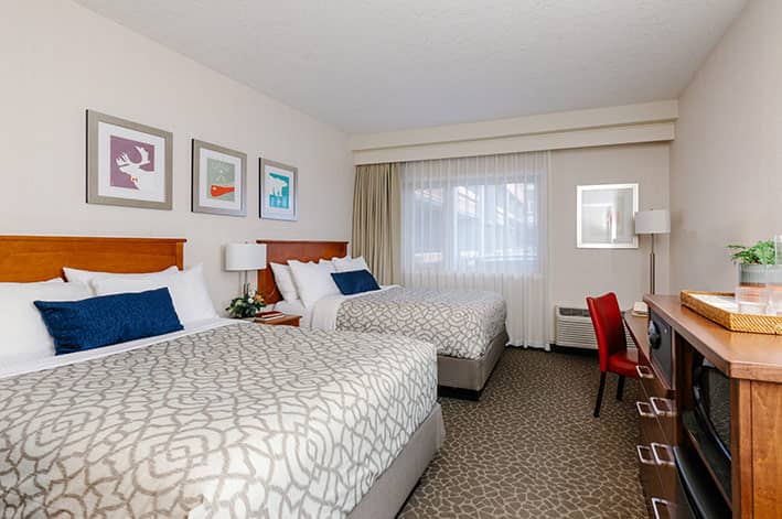 two double beds in a hotel room with colourful art above the headboard.