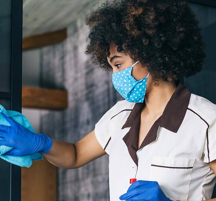 A hotel housekeeper wipes down a glass door.