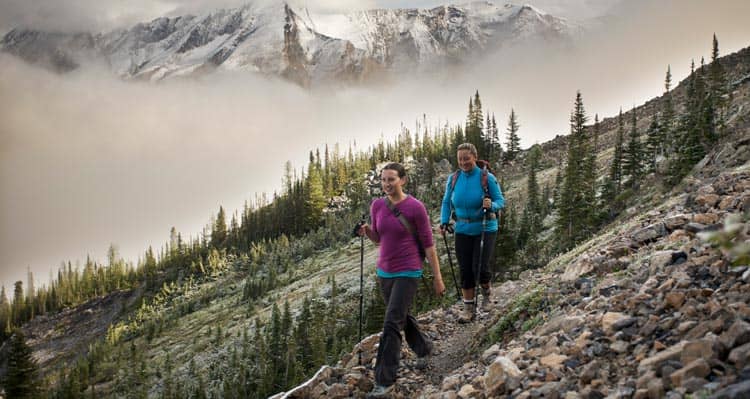 Two hikers on a rocky trail among small alpine trails.