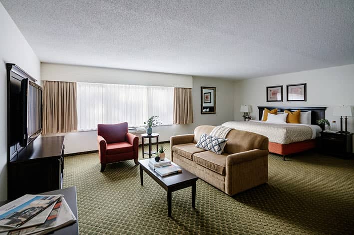 A large hotel suite with sofa, table and king bed