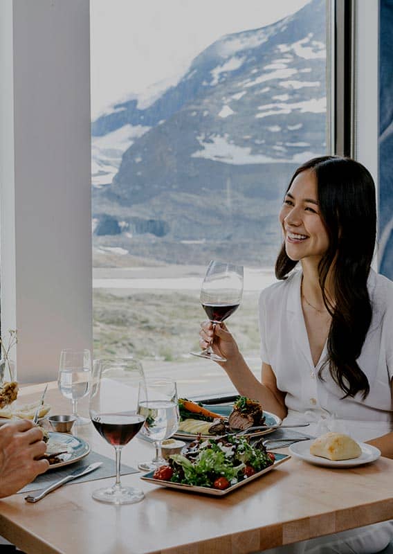 Two people sit at a windowside table for dinner.