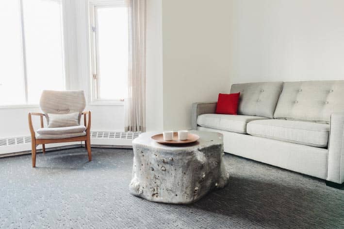 A lounge with a couch and chair, with cups on a table tray.