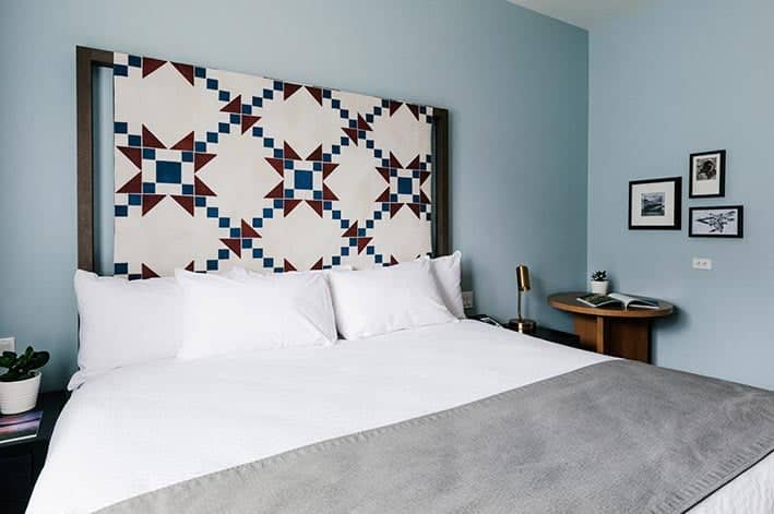 A king bed in a hotel room with a quilted headboard.