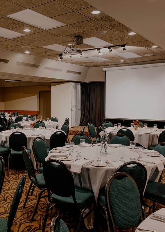 A ballroom with round tables set up for a banquet.