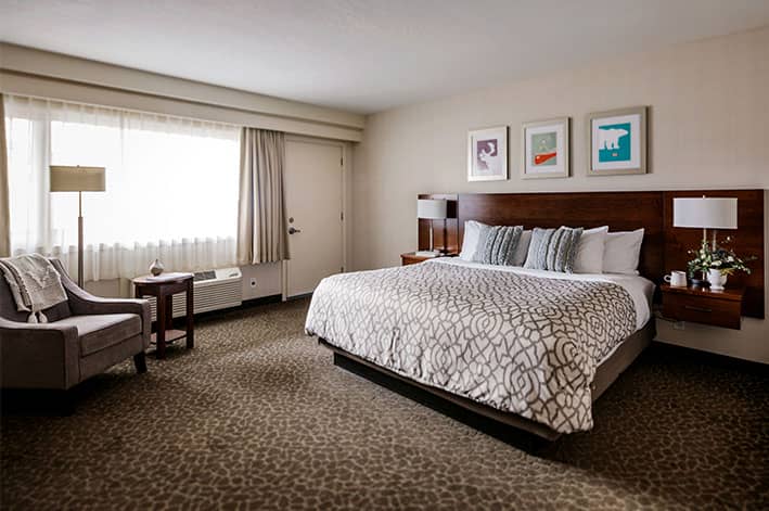 A king bed in a hotel room with colourful art above the headboard.