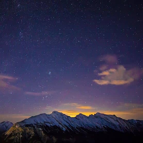 The night sky, filled with stars high above snowcapped mountains.