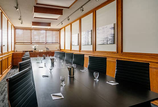 A boardroom with a long table in a wood-panelled room.