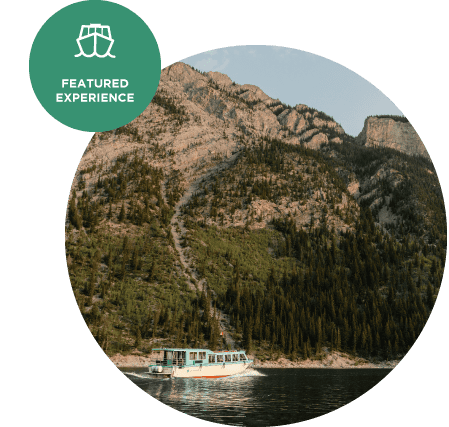 A boat cruises on a lake below a forested mountainside