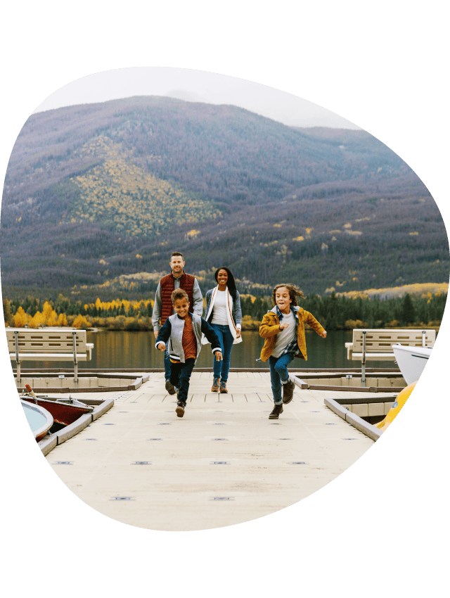 A family running down a lakeside dock.